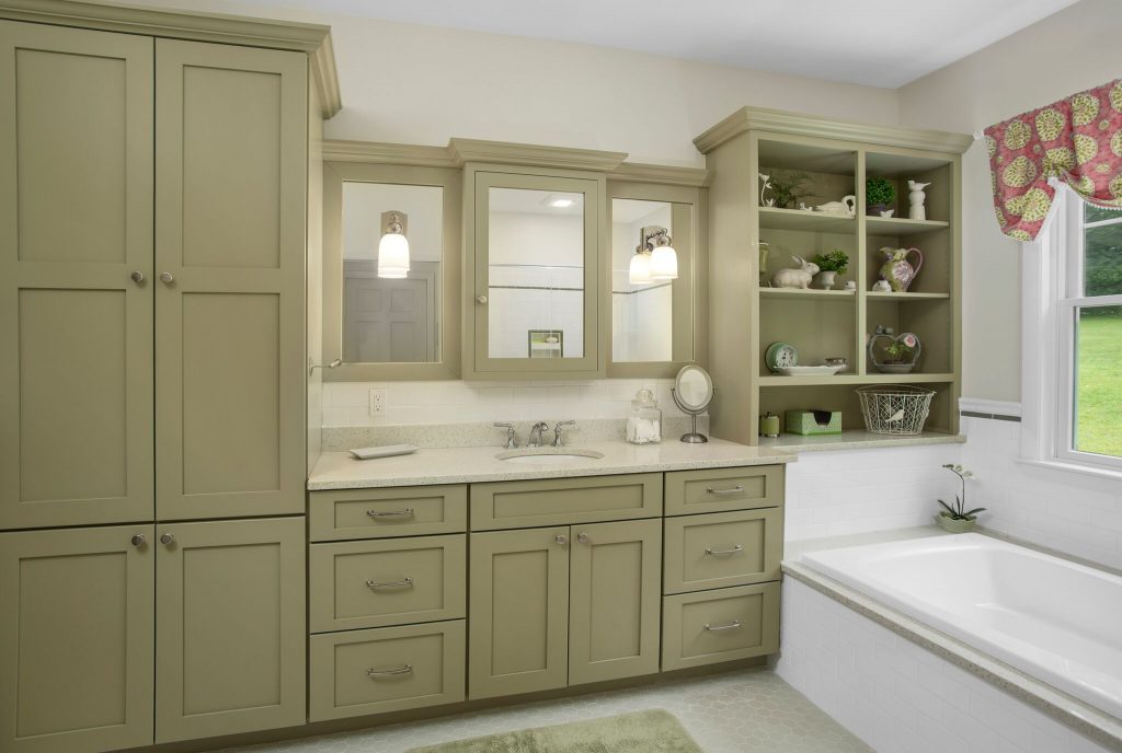 Green cabinetry bathroom with a built-in tub, open shelves, double sink, and a window with a floral valance.