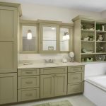 Green cabinetry bathroom with a built-in tub, open shelves, double sink, and a window with a floral valance.