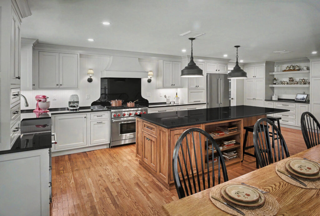 Spacious kitchen with white cabinets, black countertops, a large island, and wooden dining table with chairs.