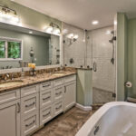 Modern bathroom with double-sink vanity, granite countertop, glass shower, bathtub, and toilet under wall art.
