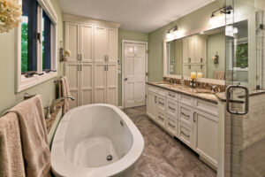 Modern bathroom with freestanding tub, double sink vanity, large mirror, storage cabinets, and neutral color scheme.