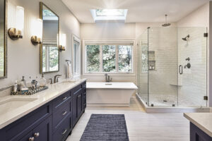 Modern bathroom with double sinks, a standalone tub under a window, and a glass-enclosed shower with white tile.
