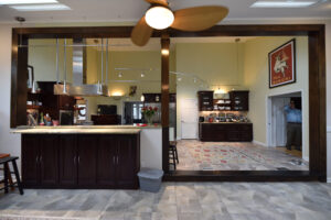Spacious open kitchen and living area with dark wood cabinets, ceiling fan, and a man standing in a doorway.