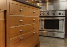 Wooden cabinets in kitchen with silver oven
